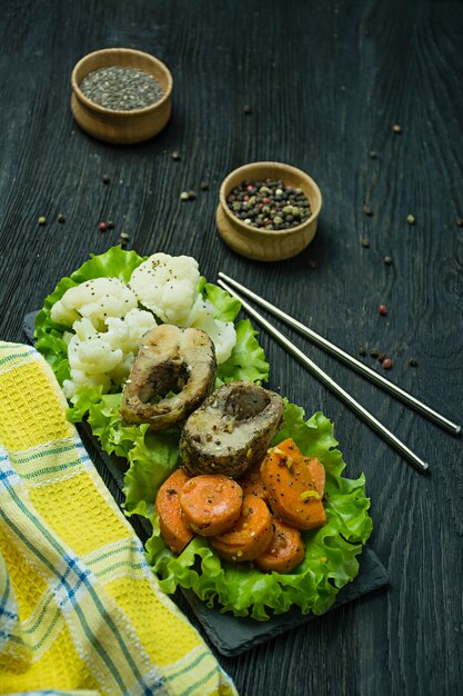 Pescado al horno con verduras. Eclisa. Nutrición apropiada. Comida ecológica. Fondo oscuro