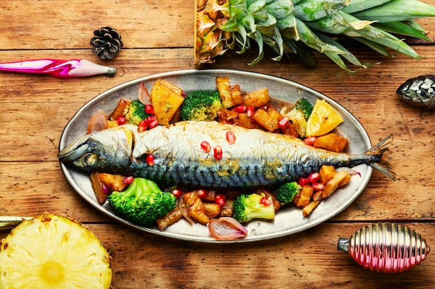 Pescado asado con piña para Navidad sobre fondo de madera rústica