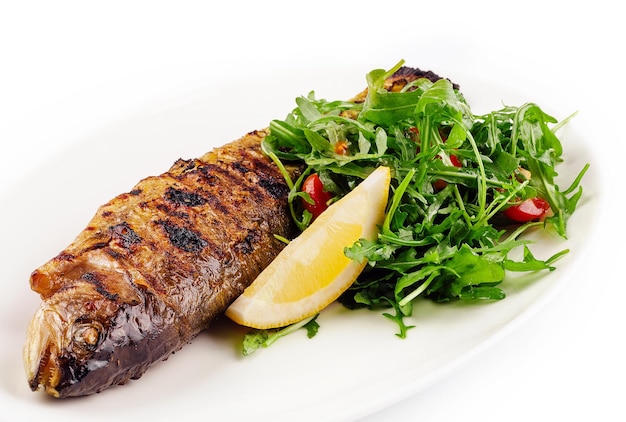 Pescado de besugo a la parrilla con rúcula de limón en un plato blanco