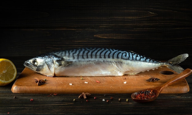 Pescado de caballa en una tabla de cortar de la mesa de la cocina con ingredientes y especias antes de cocinar una comida de pescado Espacio libre para publicidad