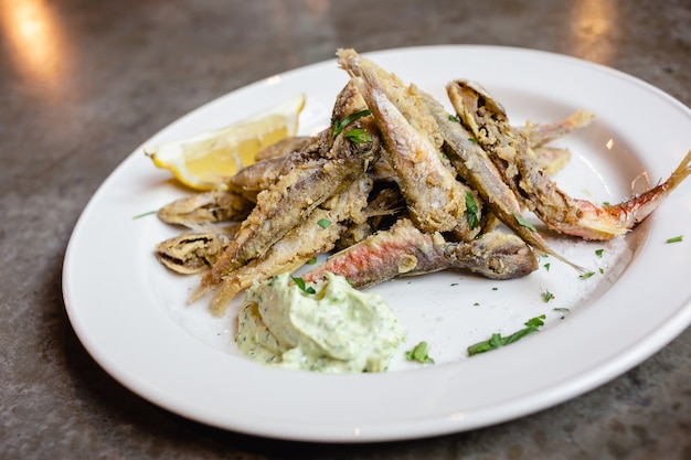 Pescado capelán frito con hierbas y salsa de limón y crema