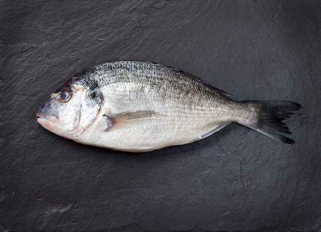 Un pescado crudo en el fondo de piedra oscura