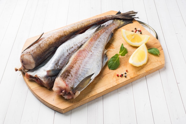 Pescado crudo fresco de abadejo en una tabla de madera con limón