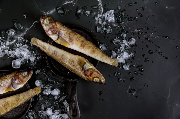 Pescado crudo fresco sano en tablero negro con hielo.