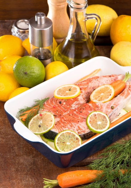 Foto pescado crudo listo para hornear filete de salmón pescado rojo y limones en rodajas en blanco