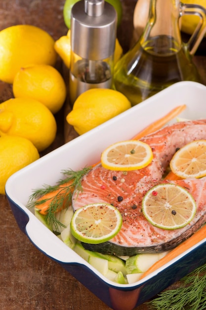 Pescado crudo listo para hornear Filete de salmón Pescado rojo y limones en rodajas en blanco