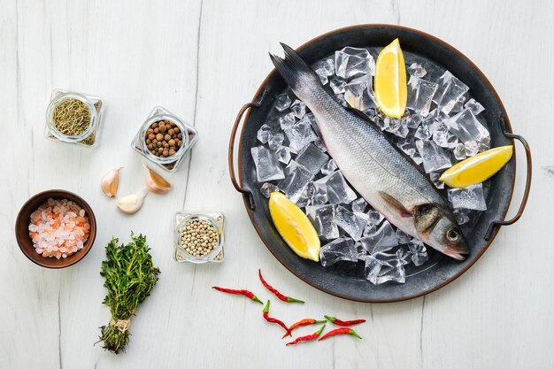 Pescado crudo de lubina con especias y hierbas en madera