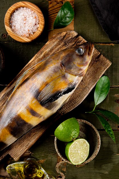 Foto pescado crudo lubina o lingcod y condimentos para cocinar sobre un fondo de madera