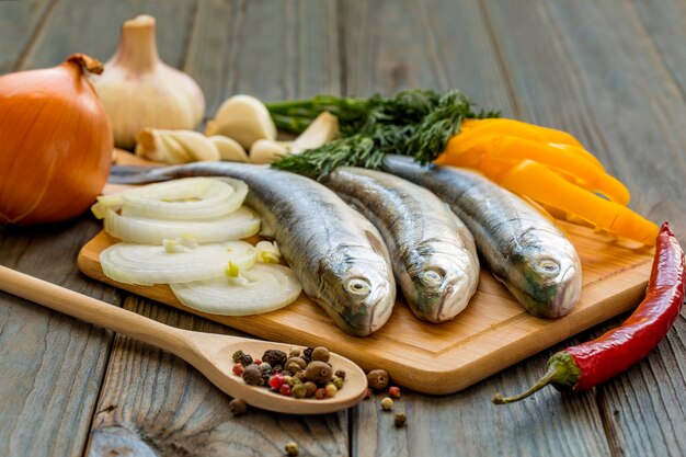 Pescado crudo en la mesa de la cocina con ingredientes para cocinar