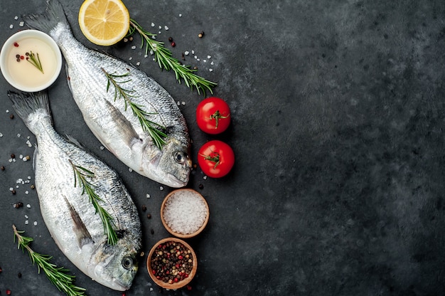 Pescado dorado crudo con especias e ingredientes tomate, razmorin, aceite de girasol, limón sobre un fondo de piedra con espacio de copia para su texto