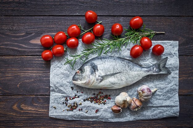 Pescado dorado crudo con verduras en pared rústica. Dorada o besugo. Vista superior, espacio de copia