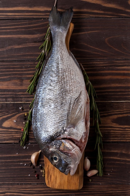 Foto pescado dorado fresco dorado ajo y romero en una mesa de madera vista superior