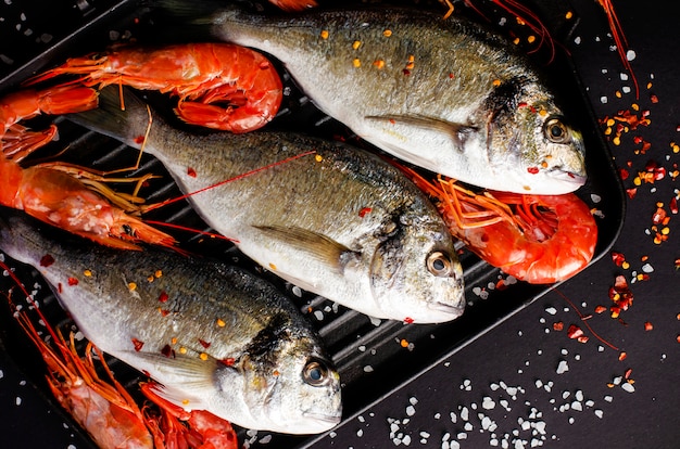 Pescado Dorado fresco y langostinos tigre en una sartén de hierro.