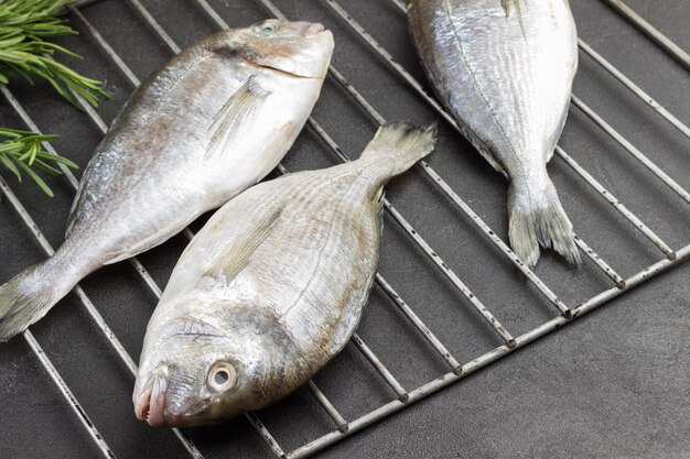 Pescado dorado fresco en rejilla metálica.