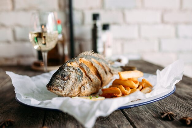 Pescado dorado frito con patatas fritas y vino blanco