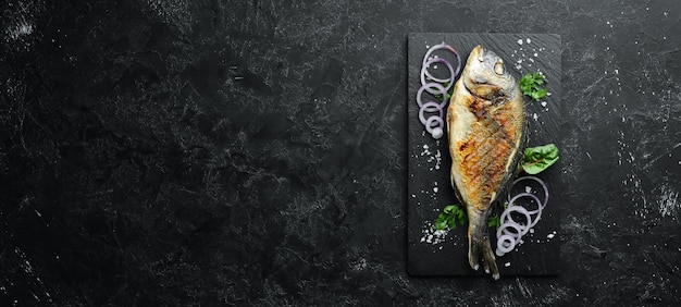 Foto pescado dorado a la parrilla en placa de piedra. vista superior. espacio de copia libre.