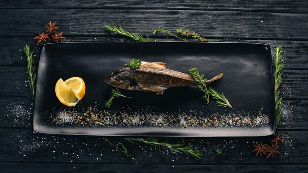 Pescado dorado con tomates cortados en cubitos y verduras Sobre un fondo de madera negra Copiar espacio