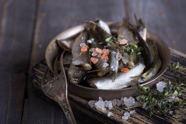 Pescado fresco de agua fría de mar fresco, como olor, sardina, anchoas sobre un fondo simple con espinacas frescas, rodajas de limón, legumbres para el concepto de una correcta nutrición natural saludable. Vista superior