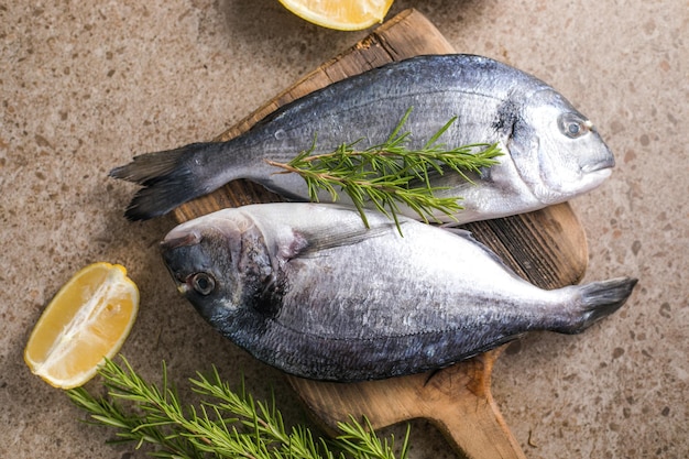 Pescado fresco dorado e ingredientes para cocinar con especias y hierbas en una mesa de hormigón gris Restaurante de mariscos dieta fondo de comida saludable Vista superior plana con espacio de copia