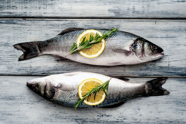 Pescado fresco lubina. Pescado crudo lubina con ingredientes especias y hierbas sobre fondo de madera