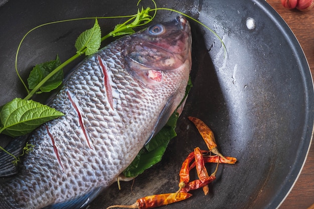 Pescado fresco en una sartén y especias para cocinar