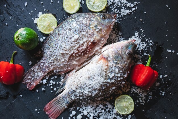 Pescado fresco de tilapia con sal y condimento para cocinar.