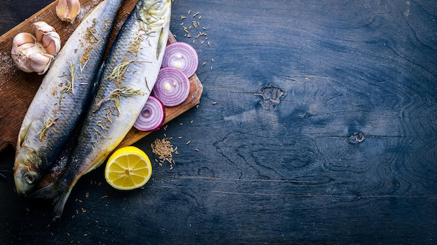 Pescado fresco con verduras, especias y aceite Sobre un fondo de madera negra Espacio libre para texto Vista superior