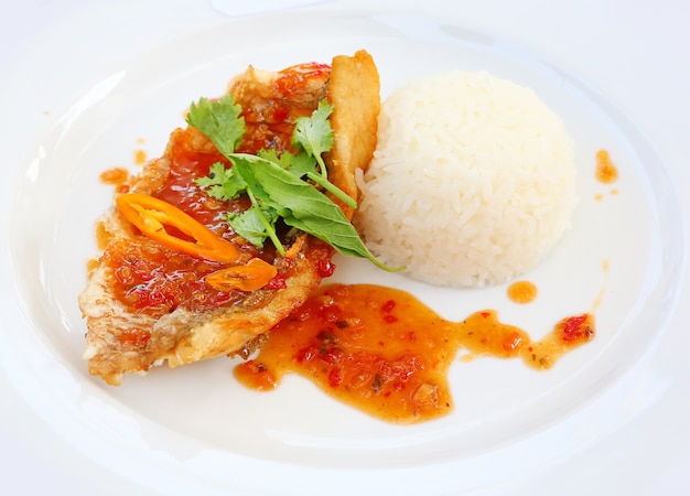 pescado frito y arroz en un plato con albahaca y pimienta