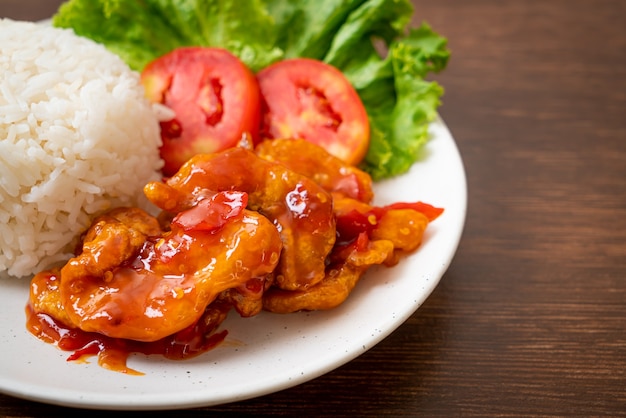 Pescado frito cubierto con salsa de chile de 3 sabores con arroz en la placa blanca.