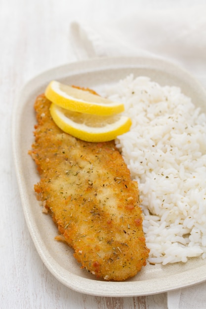 Pescado frito con limón y arroz hervido en un plato