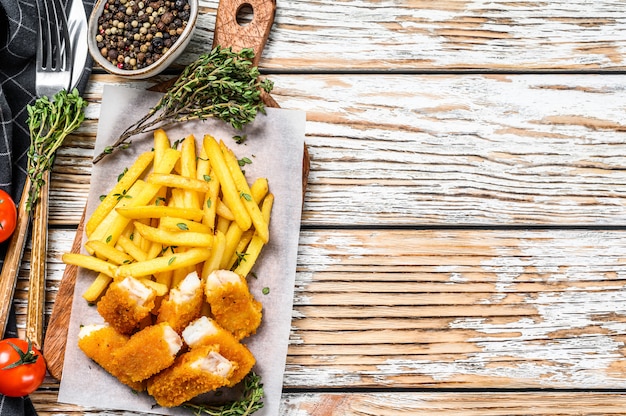 Pescado frito con patatas fritas británico en la tabla de madera blanca.