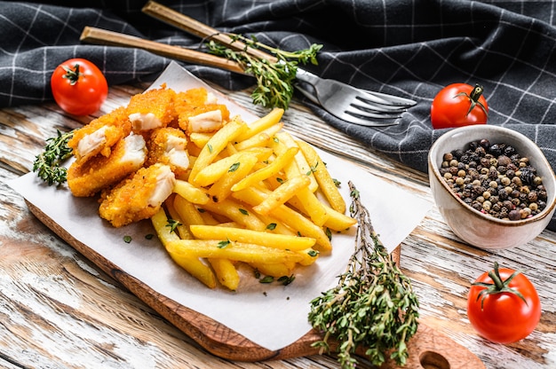 Foto pescado frito con patatas fritas británico en la tabla de madera blanca.