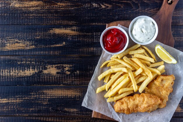 Pescado frito con patatas fritas en un fondo de madera. Comida rápida británica. Recetas. Merienda a la cerveza. Cocina inglesa.