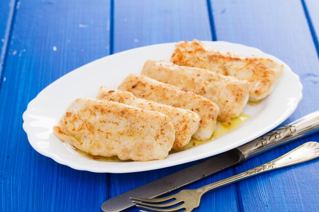 Pescado frito en plato blanco sobre superficie de madera