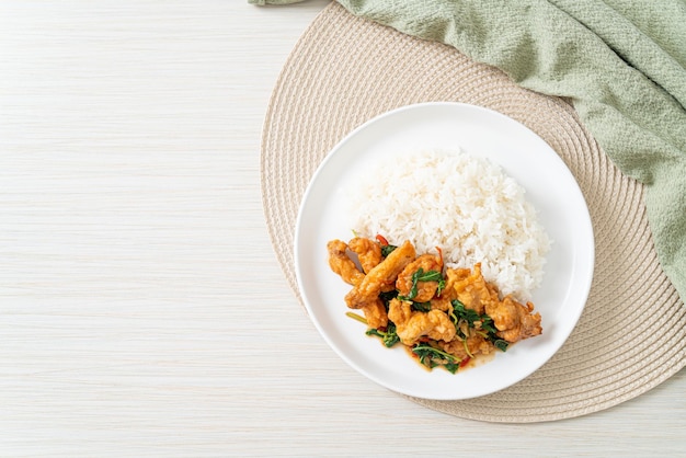 pescado frito salteado con albahaca y chile al estilo tailandés cubierto con arroz - estilo de comida asiática