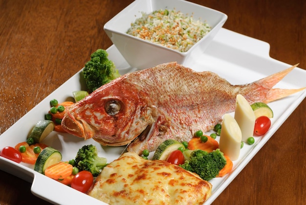 Pescado frito con verduras en mesa de madera