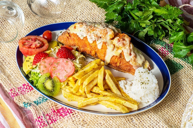 Pescado gratinado con ensalada de frutas y papas fritas