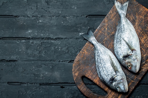 Pescado de mar crudo dorado en una tabla de cortar