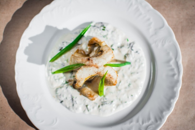 Pescado de mar guisado en salsa de leche y cebolla Deliciosa comida dietética Servido en un plato blanco