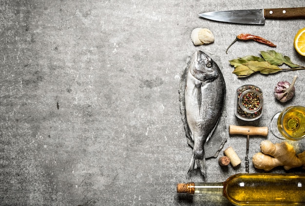 Pescado marino con vino y una variedad de especias y hierbas sobre hormigón