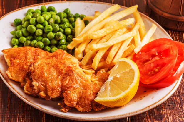 Pescado y papas fritas con verduras en un plato