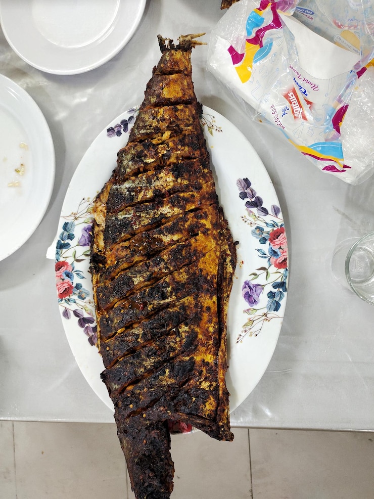 un pescado a la parrilla está en un plato con un cuchillo y una placa con un tenedor