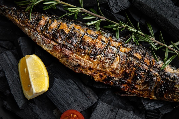 Pescado a la parrilla en una parrilla con limones y tomates