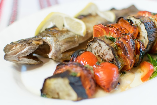 Pescado a la parrilla y verduras a la parrilla en un plato blanco