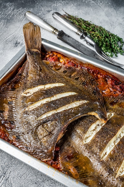 Pescado plano de solla o platija al horno en salsa de tomate en bandeja de horno