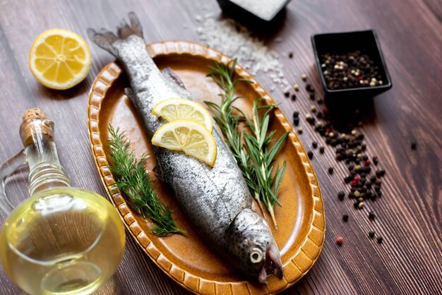 Un pescado en un plato con limones y hierbas.