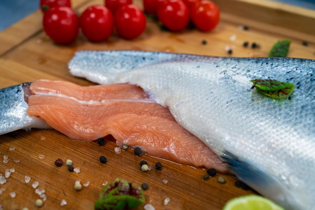 Pescado de salmón crudo fresco en la tabla de madera de la cocina con especias y lima