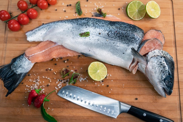 Pescado de salmón crudo fresco en la tabla de madera de la cocina con especias y lima