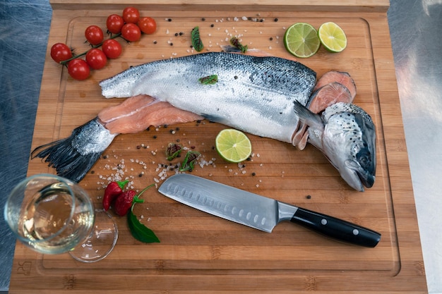 Pescado de salmón crudo fresco en la tabla de madera de la cocina con especias y lima