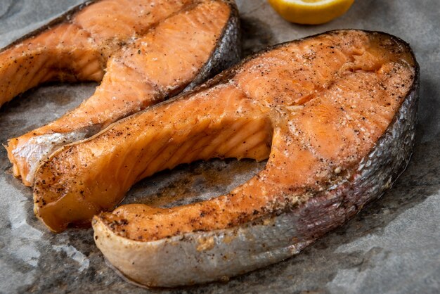 Foto pescado salmón a la plancha sobre fondo negro.